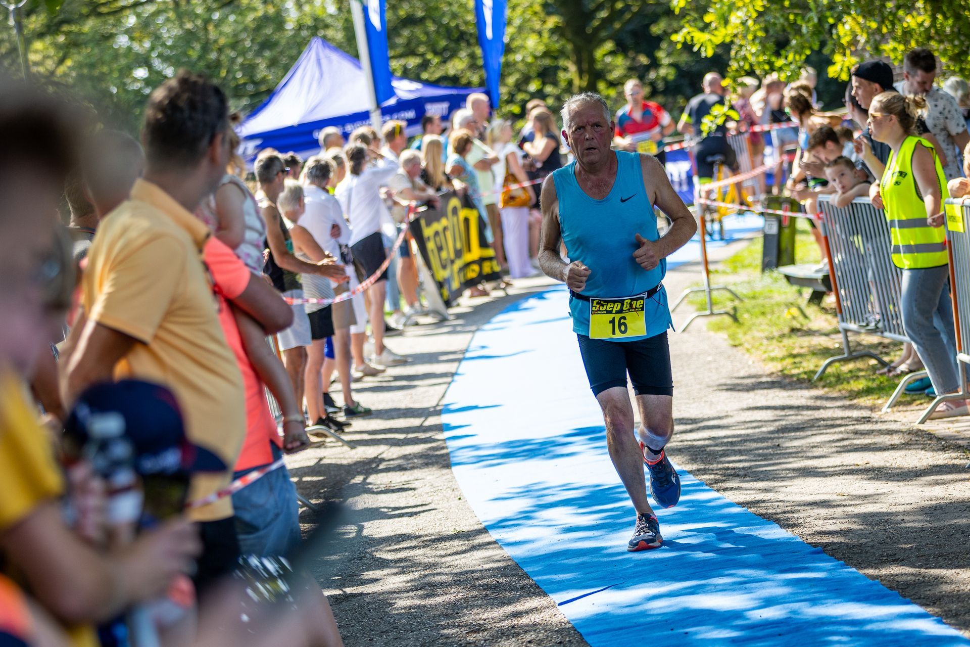 Een man rent een marathon voor een grote groep mensen.