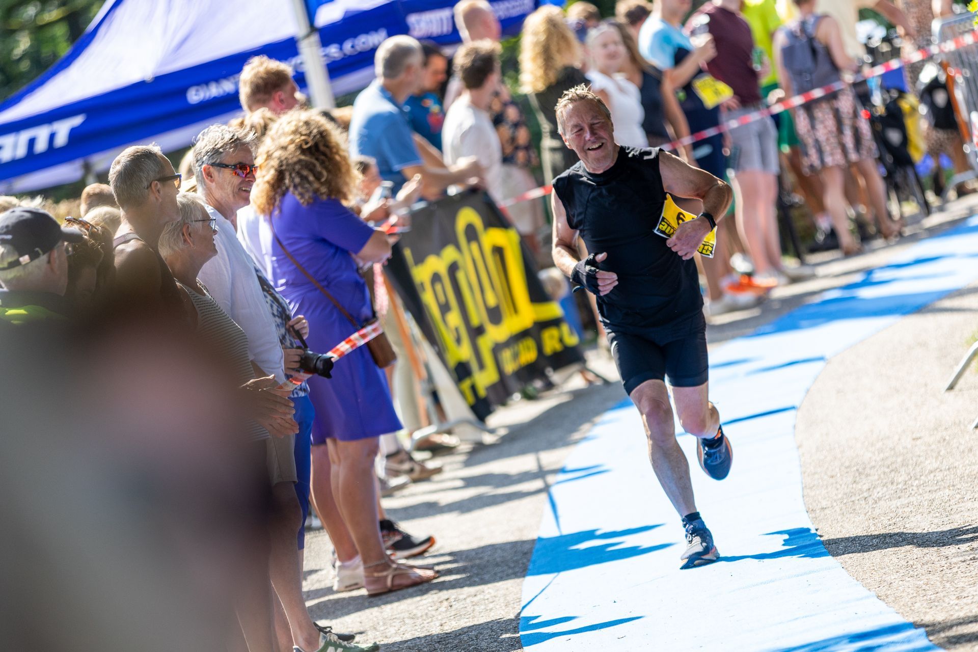 Een man rent een marathon voor een grote groep mensen.