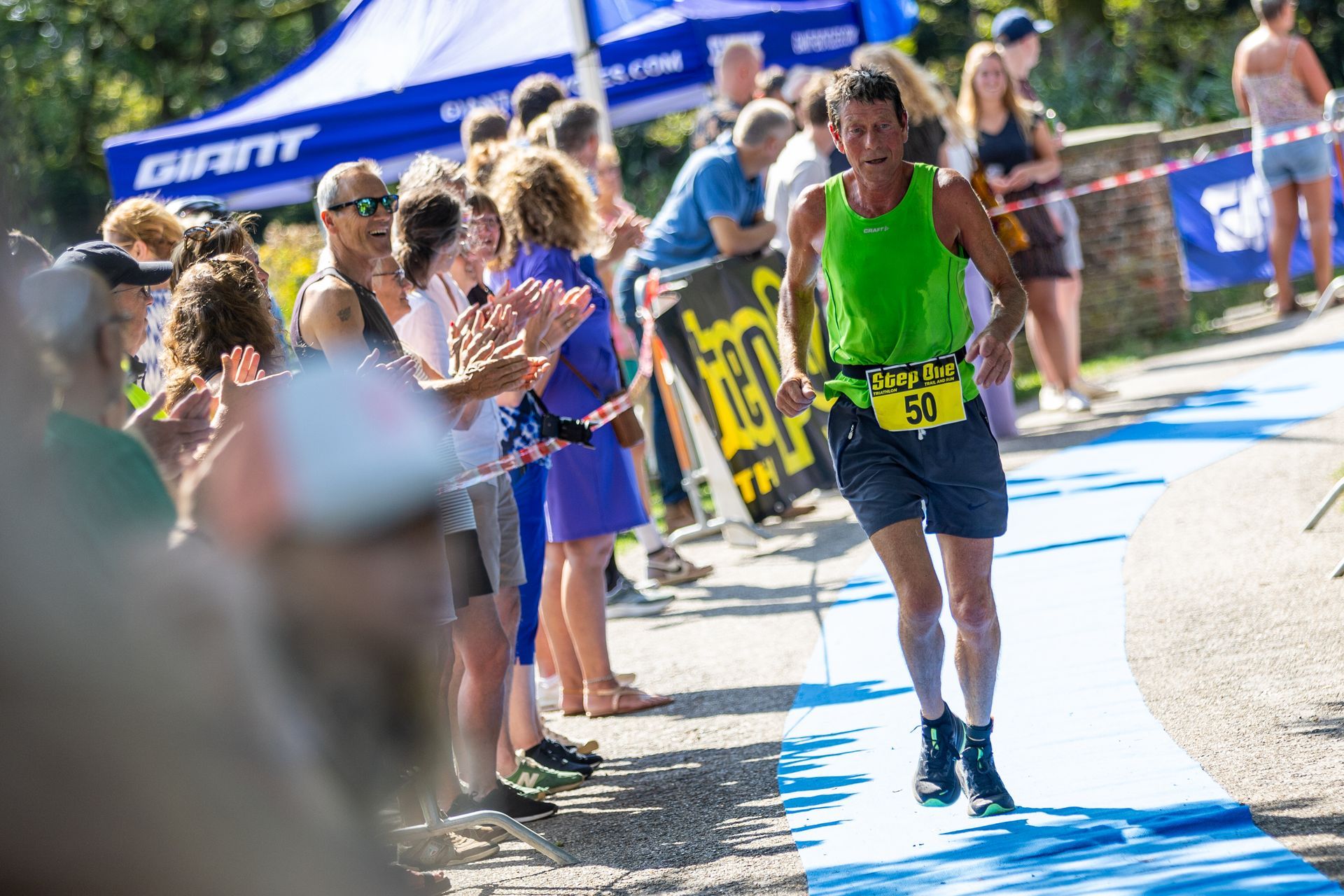 Een man rent een marathon voor een grote groep mensen.