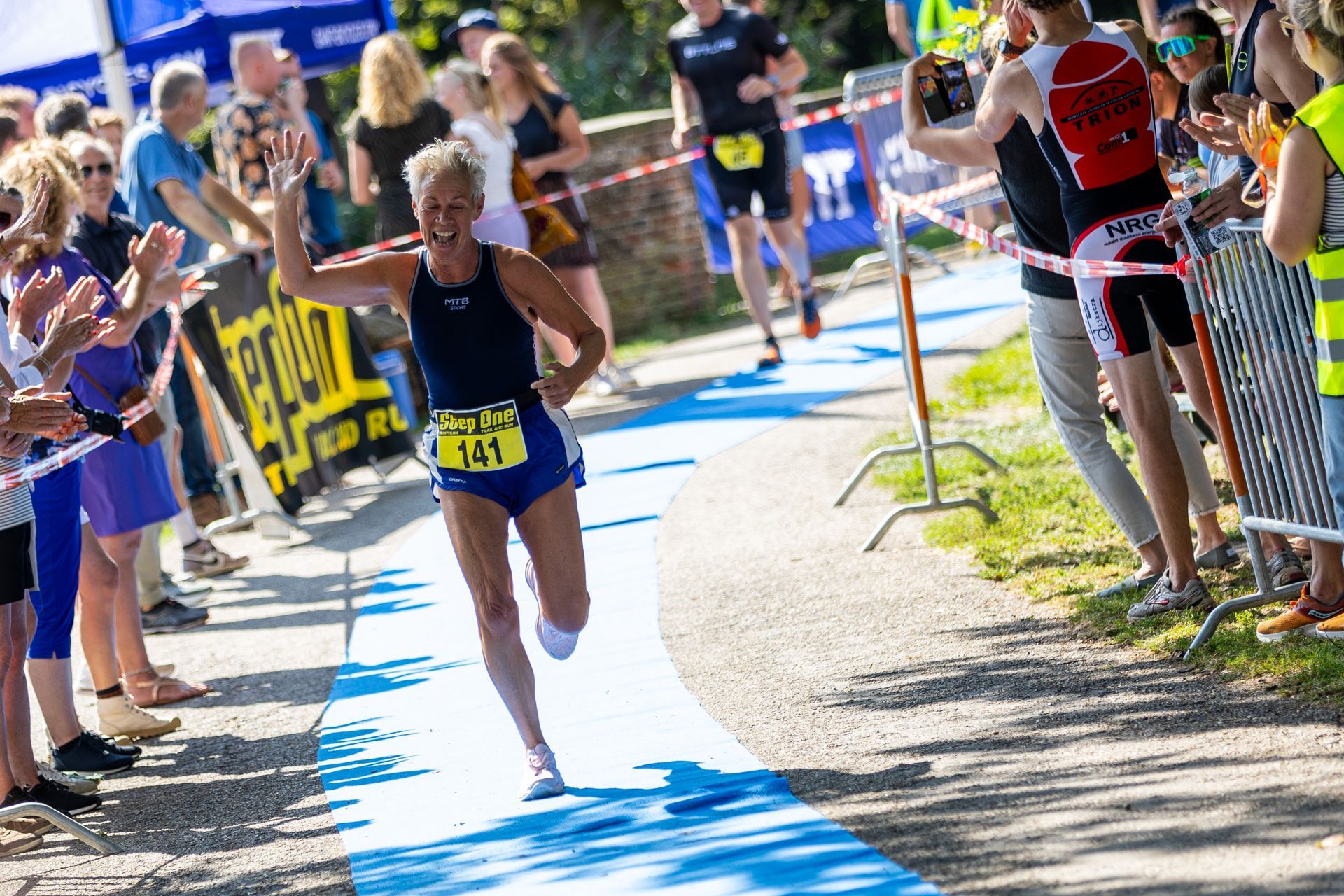 Een vrouw rent een marathon voor een grote groep mensen.