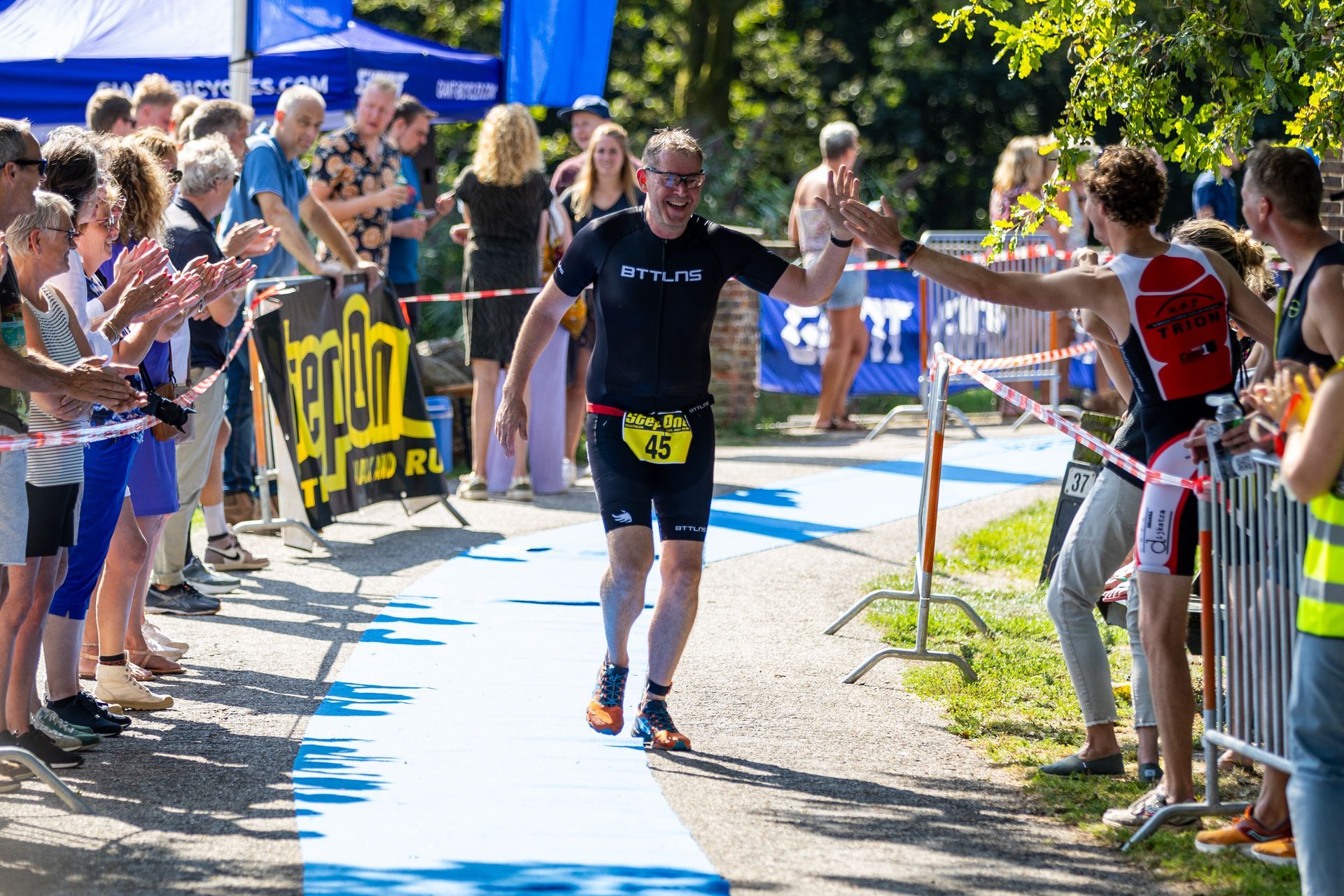Een man loopt over een blauwe loper voor een menigte mensen.