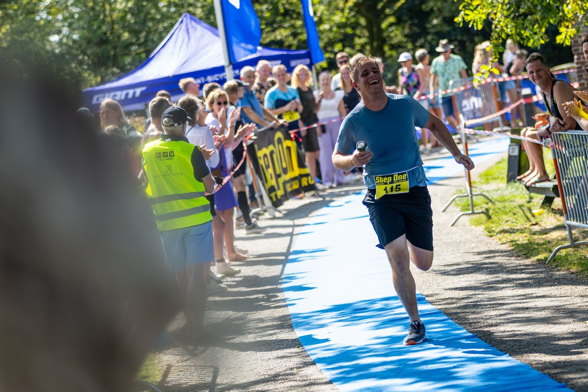 Een man rent over een blauwe loper voor een menigte.