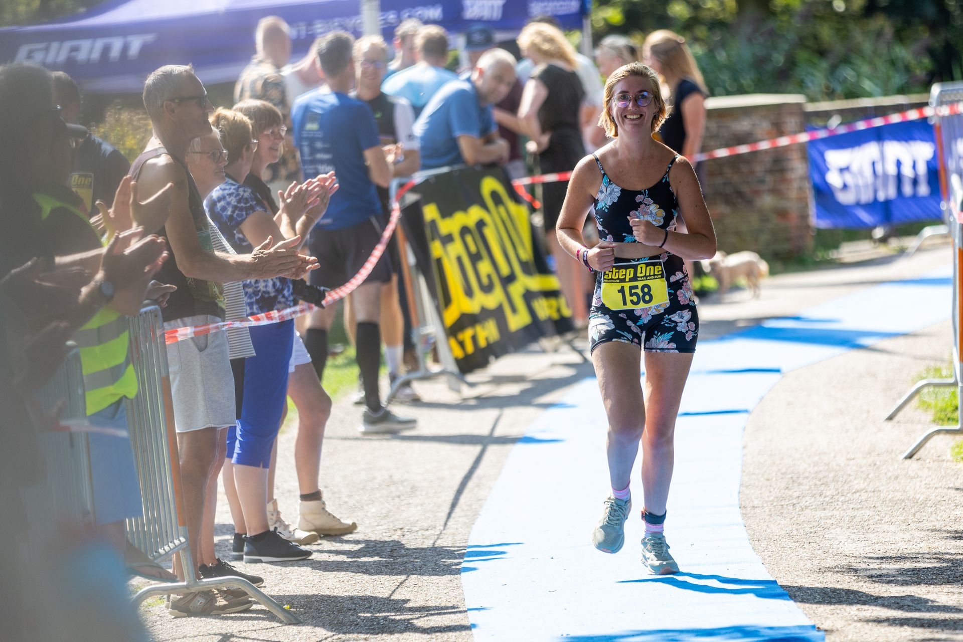 Een vrouw rent een marathon voor een grote groep mensen.