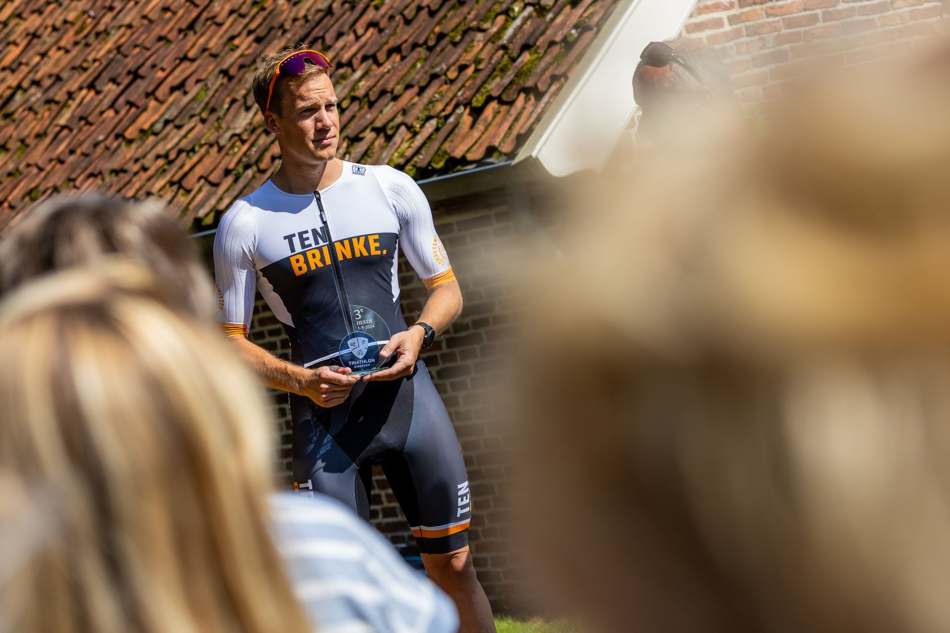 Een man in een triatlonpak staat voor een groep mensen.