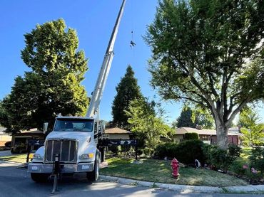 A large white truck with a crane attached to it is parked in front of a house.