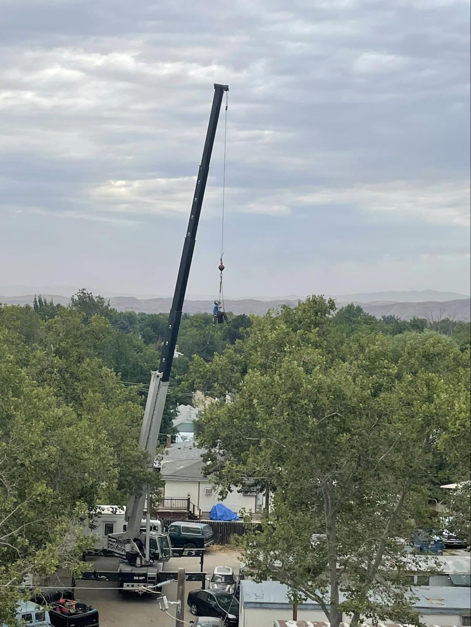 An aerial view of a crane in a parking lot with trees in the background.