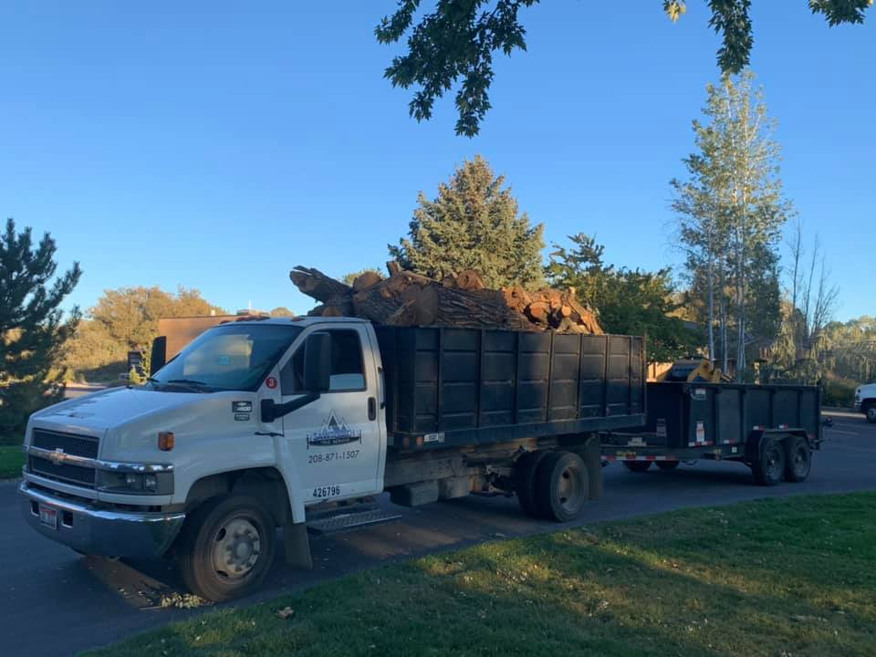 A dump truck with a trailer attached to it is parked in a driveway.
