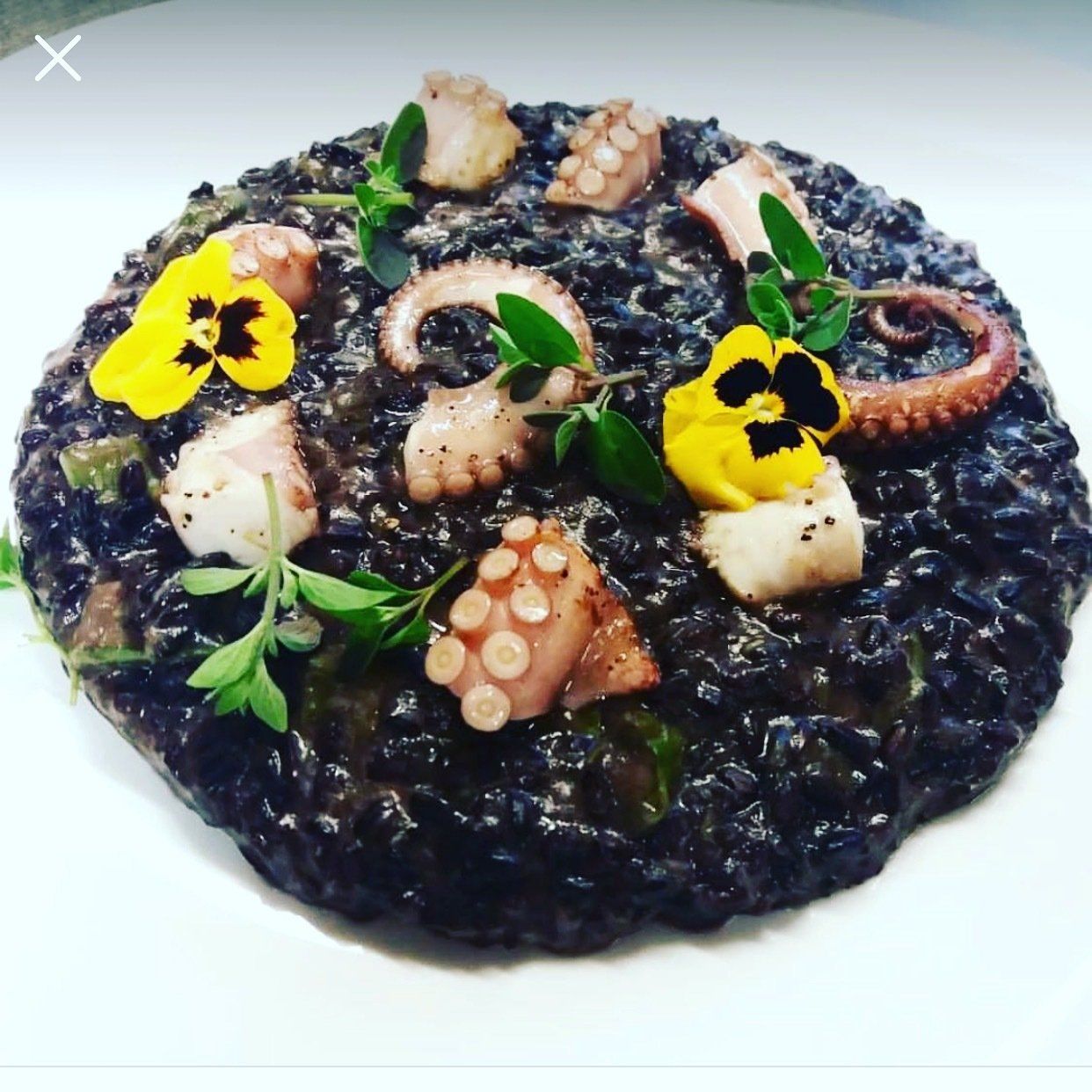 Un piatto di cibo con sopra un polpo e dei fiori