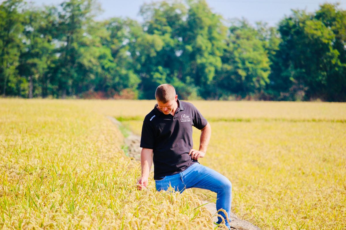 Un uomo in giacca e cravatta è in piedi davanti a un tavolo pieno di carte e confezioni di riso