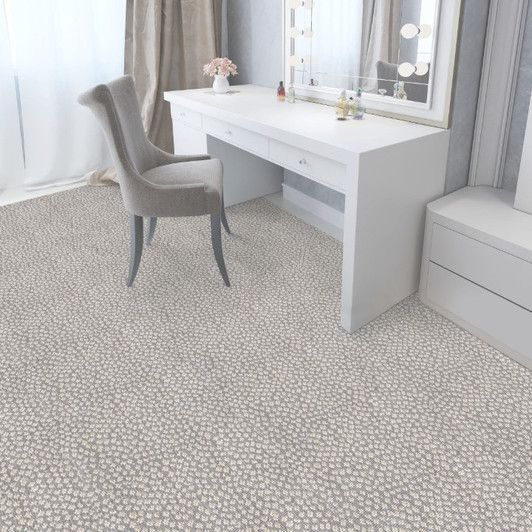 Bedroom with white vanity, gray chair, and patterned light-colored carpet.