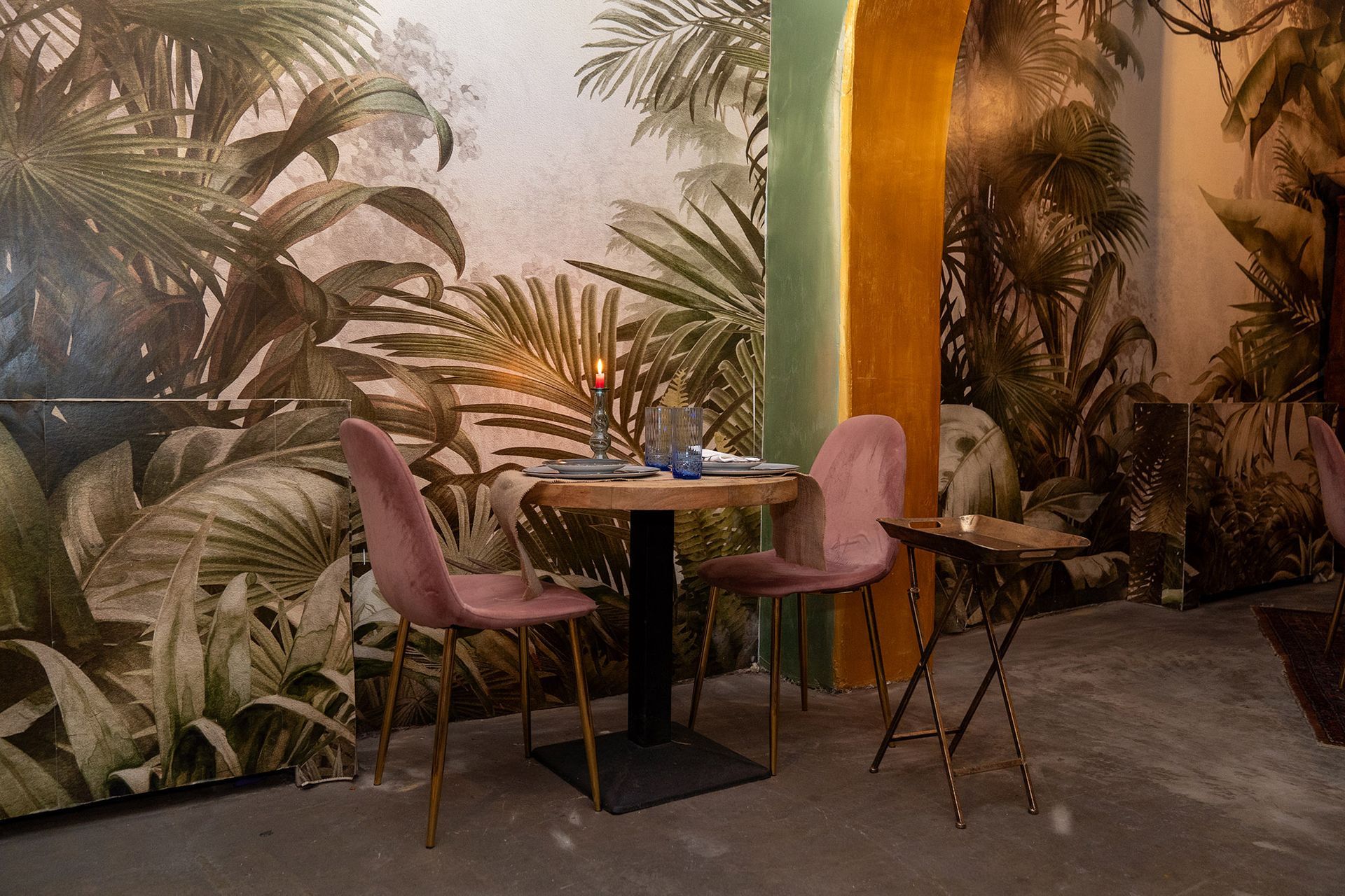 Una sala da pranzo con tavolo e sedie di fronte a una carta da parati raffigurante la giungla.