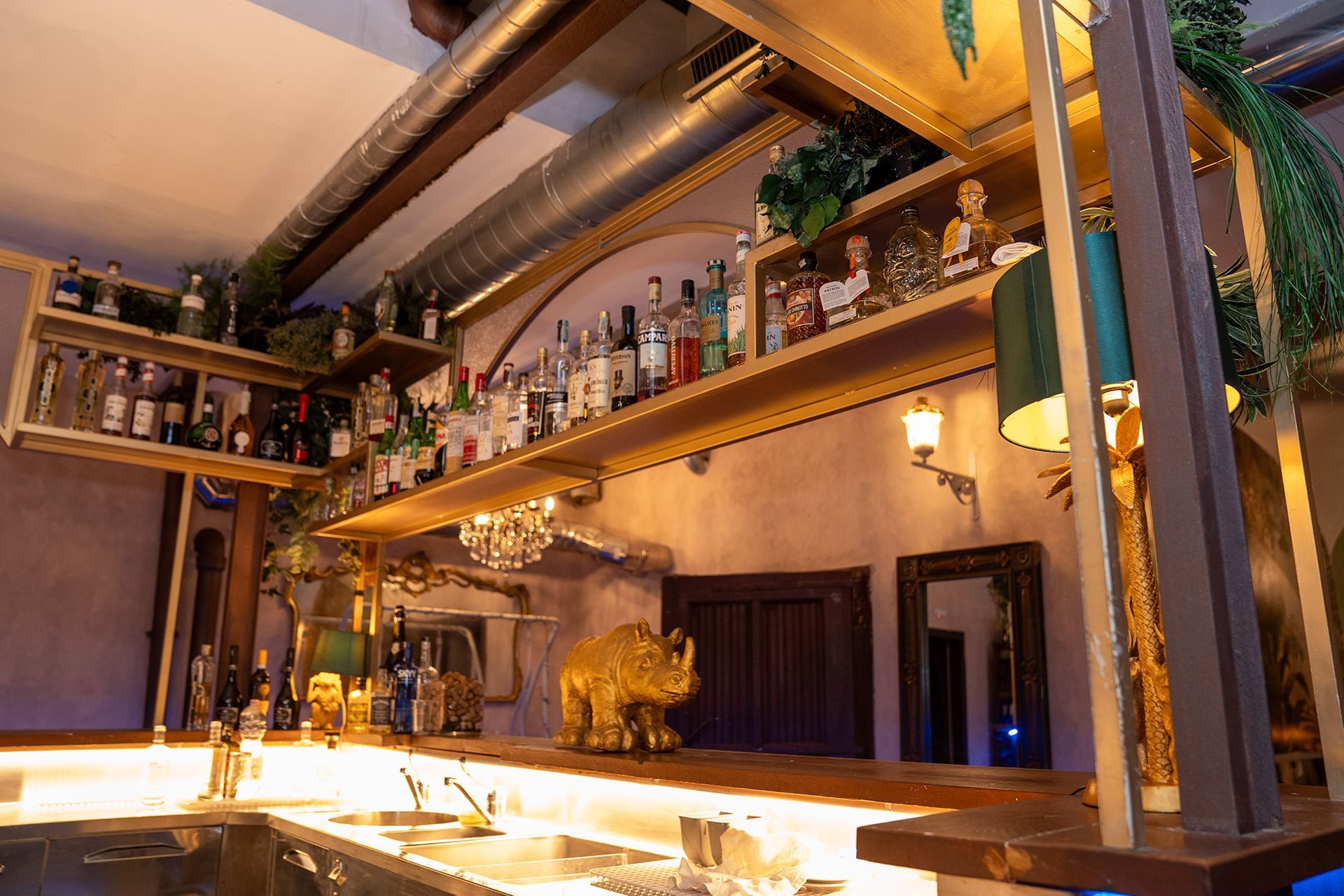 Un bar con bottiglie sugli scaffali e una statua di rinoceronte sul bancone.