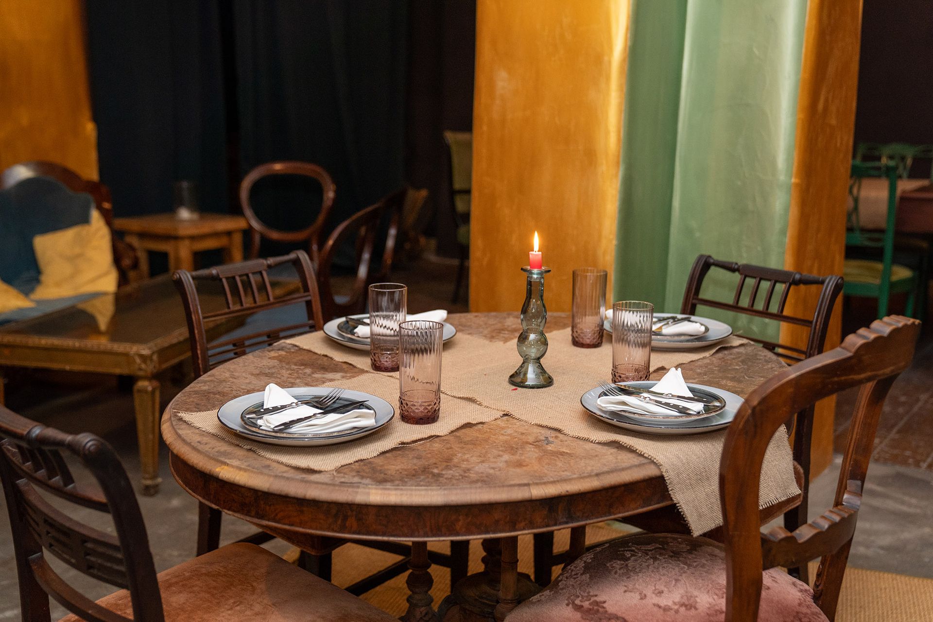 Un tavolo di legno con piatti, bicchieri e una candela sopra.