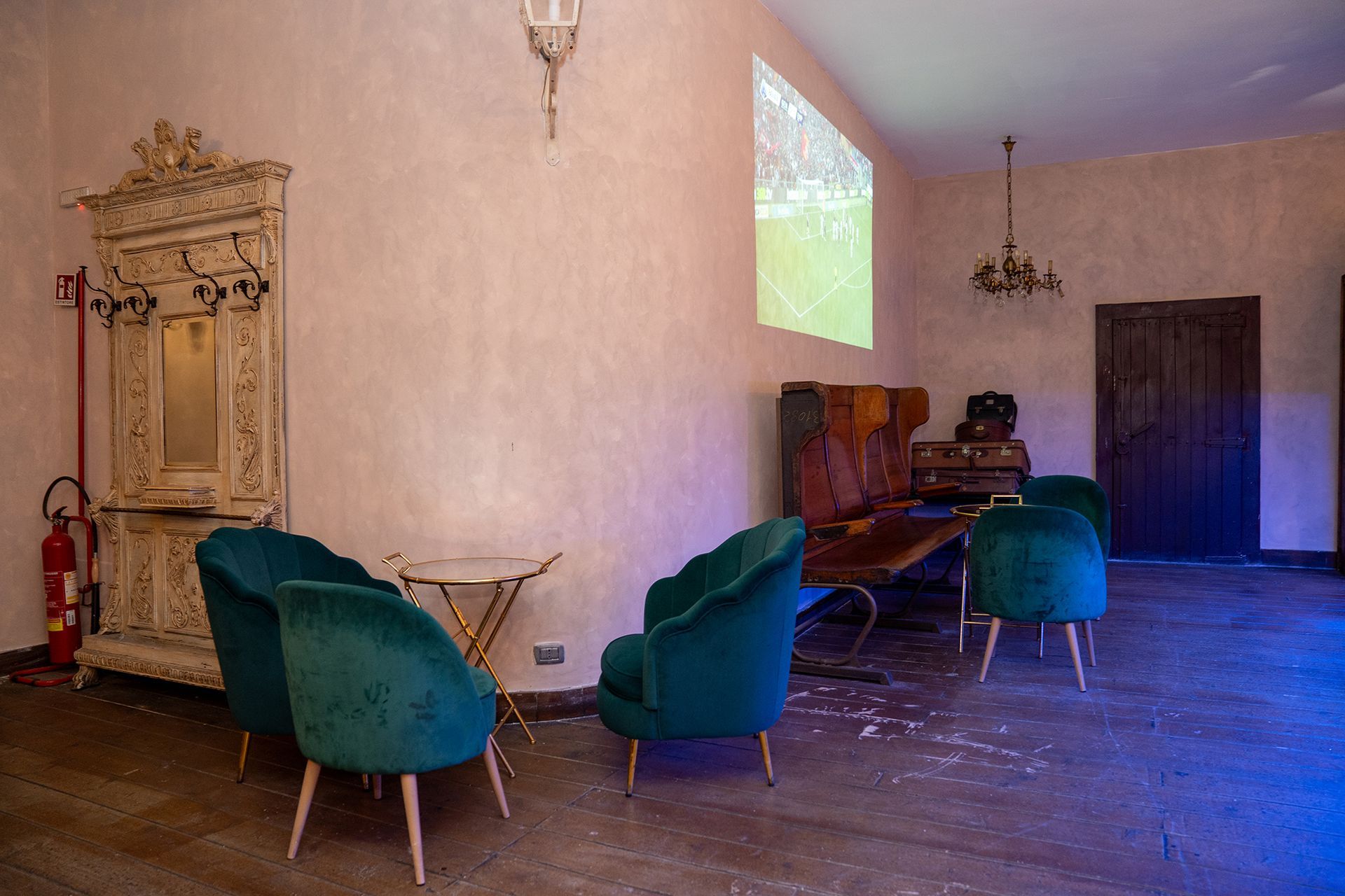 Una stanza con sedie verdi e uno schermo per proiettore sul muro.