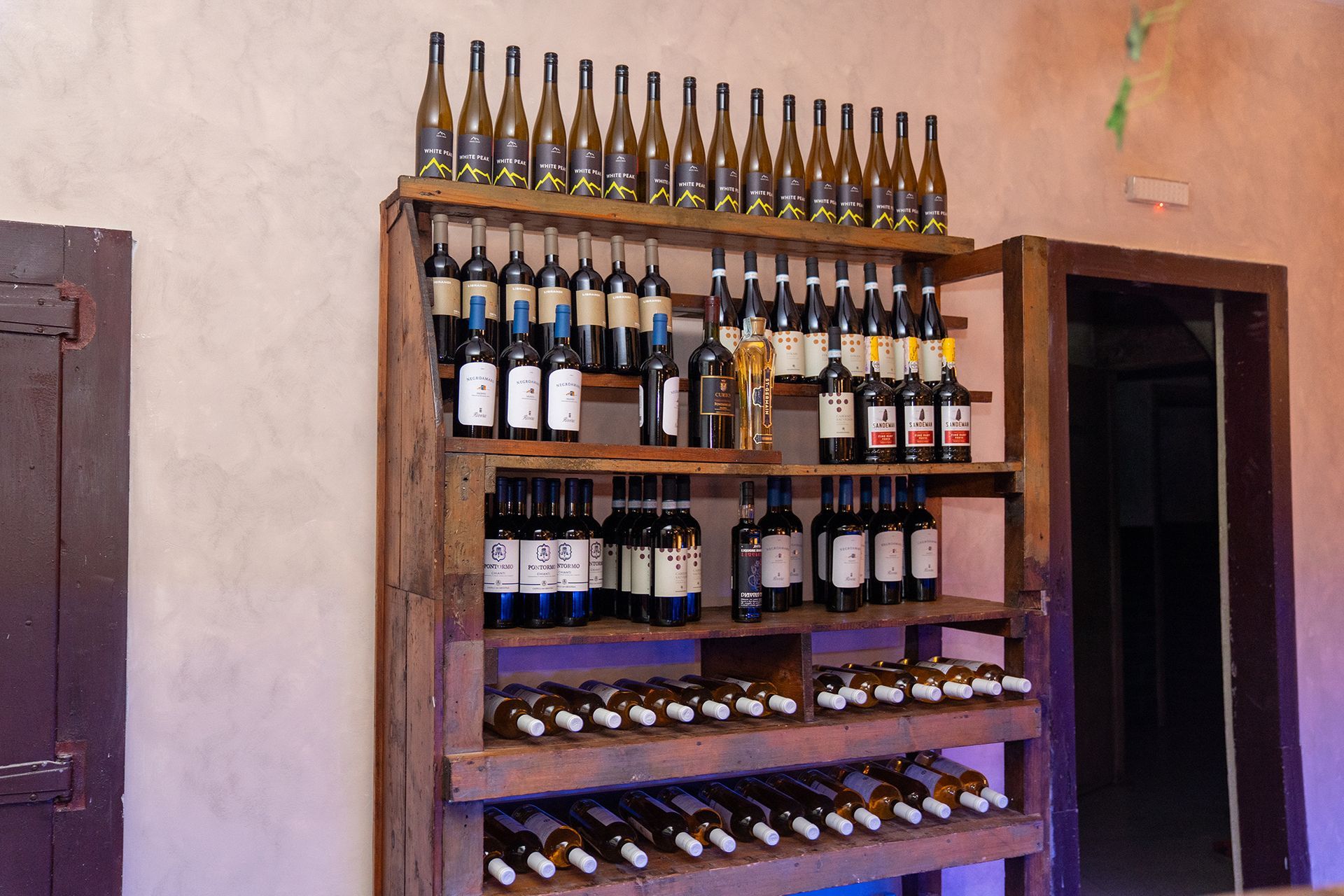 Uno scaffale di legno pieno di bottiglie di vino