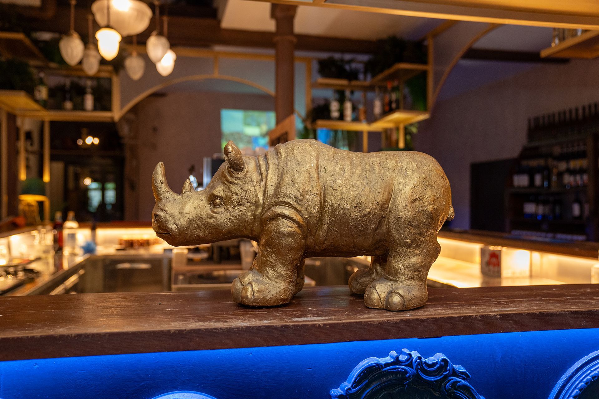 Una statua di rinoceronte dorato è seduta sul bancone di un bar.