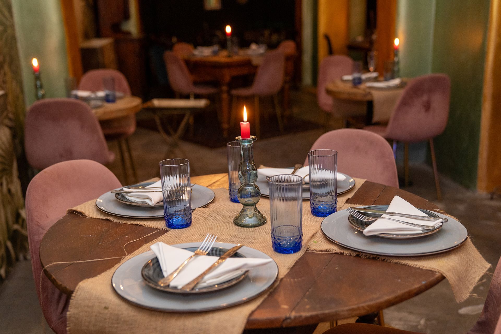 Un tavolo apparecchiato per quattro persone in un ristorante con piatti, bicchieri e candele.