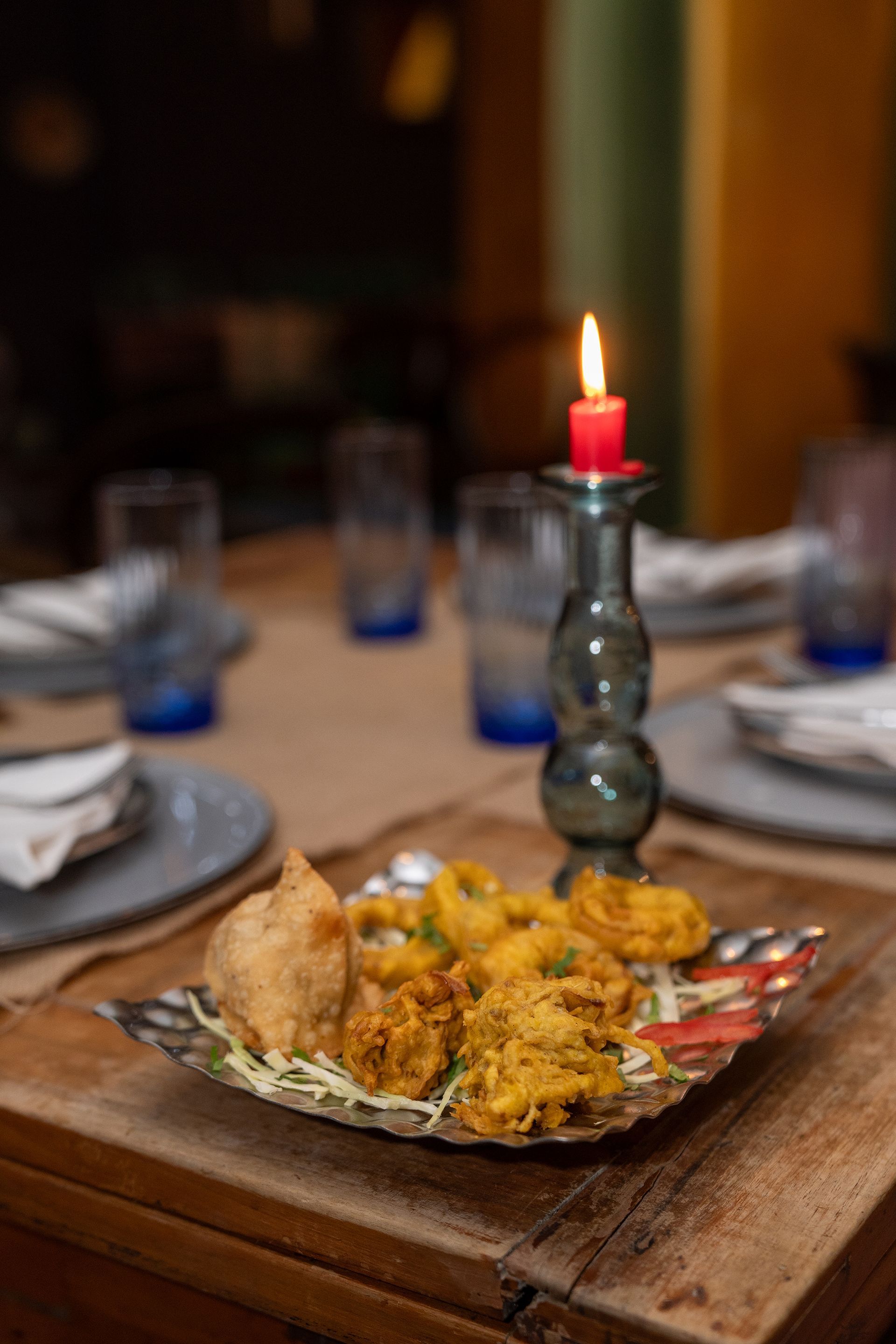 Un piatto di cibo è appoggiato su un tavolo di legno accanto a una candela.