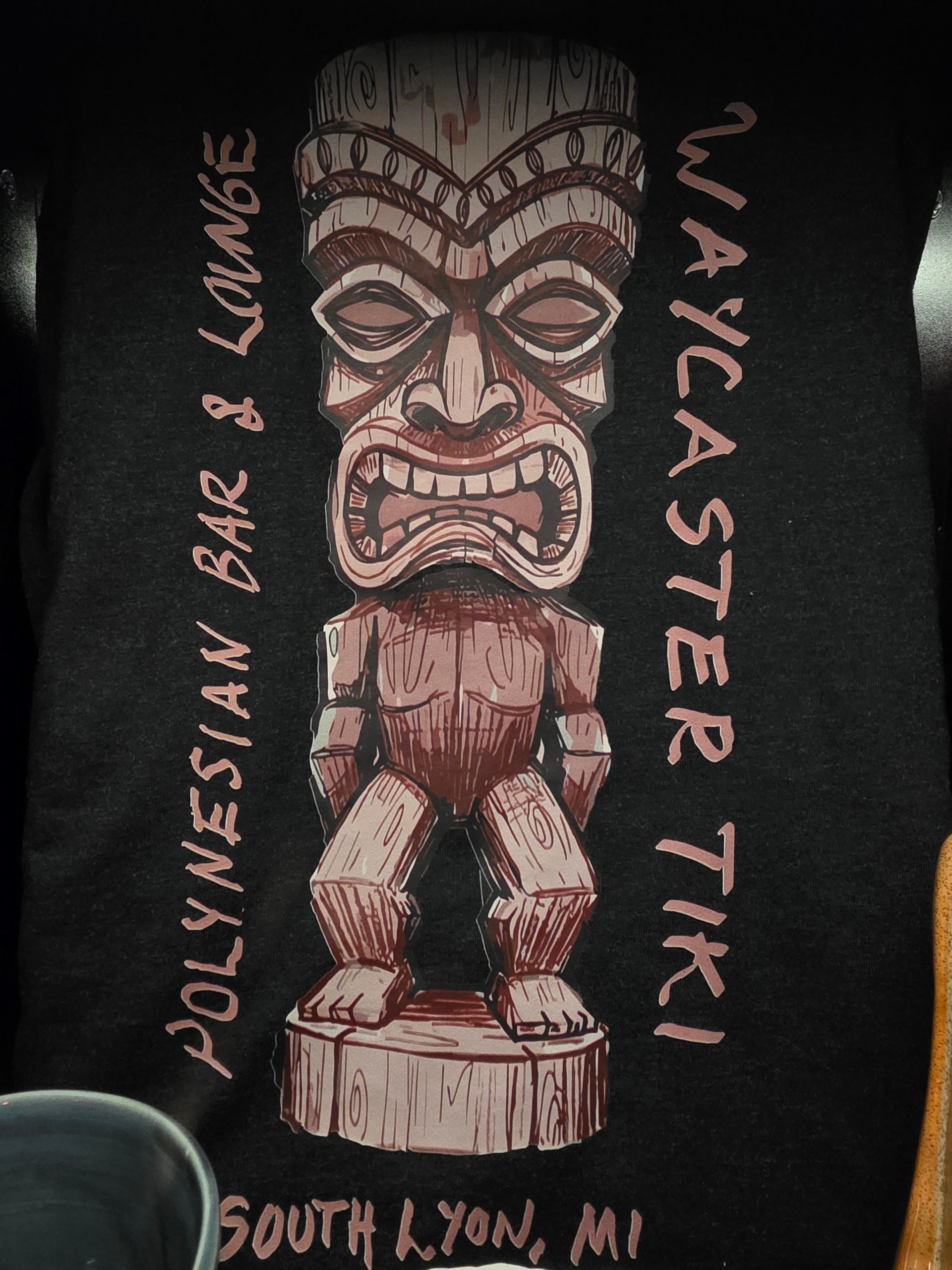 Tropical fruit arrangement on a beach at sunset, with tiki torches and a distant island.