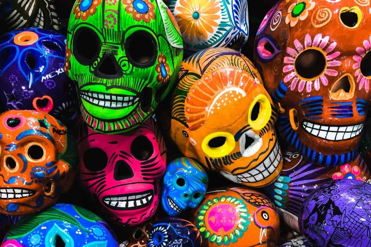 Colorful, decorated sugar skulls, some smiling, stacked together. Day of the Dead display.