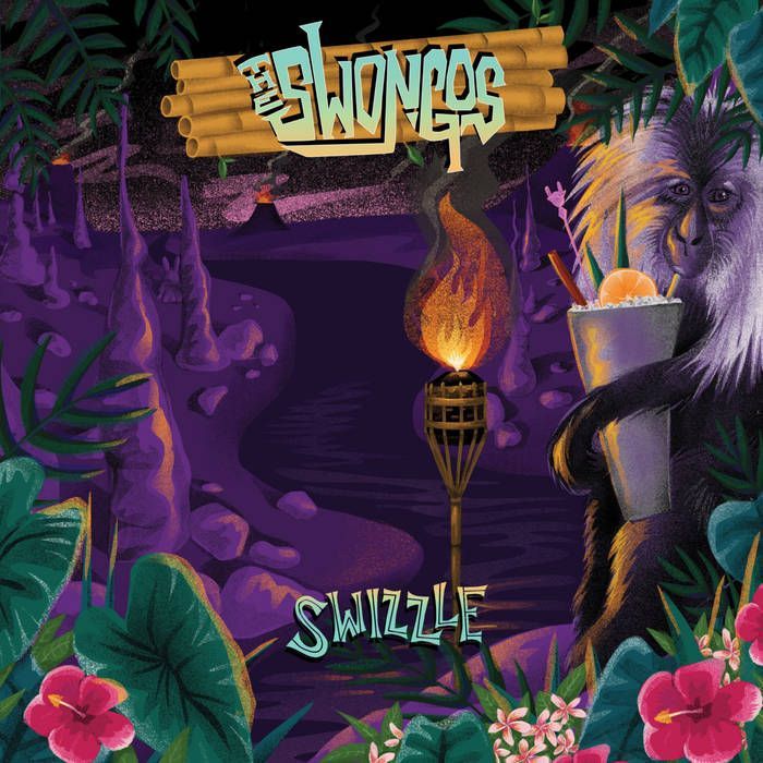 Three people pose behind a counter filled with objects. A person in the center holds a bust; all three smile.