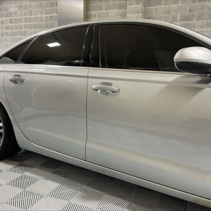 A silver car is parked in a garage next to a brick wall.