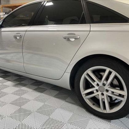 A silver car is parked on a checkered floor in a garage.
