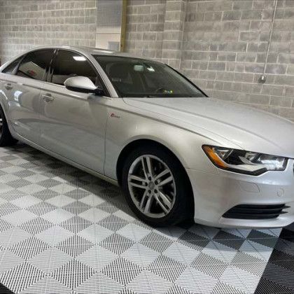A silver audi a6 is parked in a garage on a checkered floor.