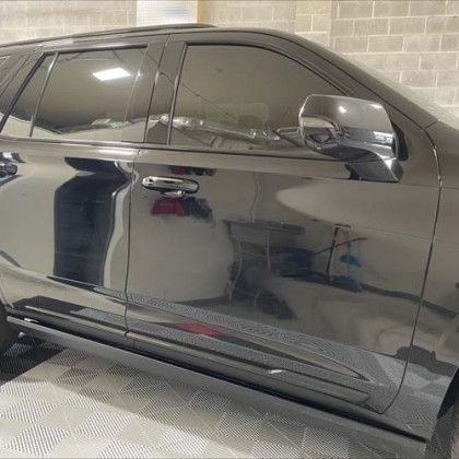 A black car is parked in a garage next to a brick wall.