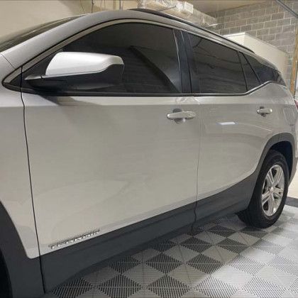 A silver gmc terrain is parked in a garage.
