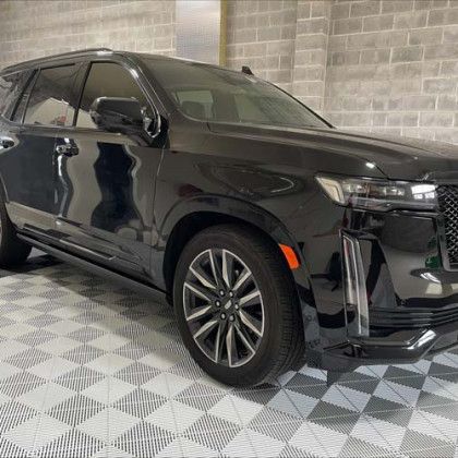 A black cadillac escalade is parked in a garage.