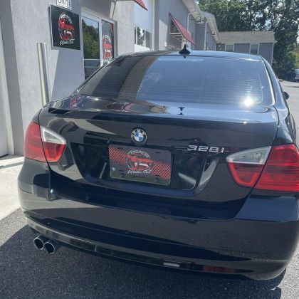 A black bmw 3 series is parked in front of a building.