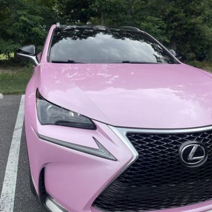A pink lexus nx is parked in a parking lot.