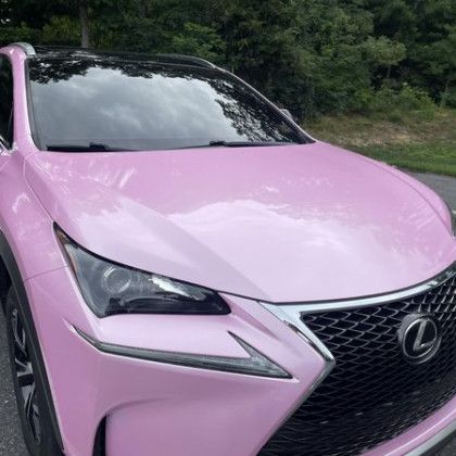 A pink lexus nx is parked on the side of the road.
