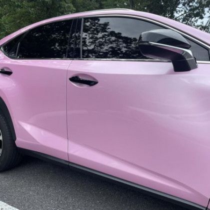 A pink car is parked on the side of the road.