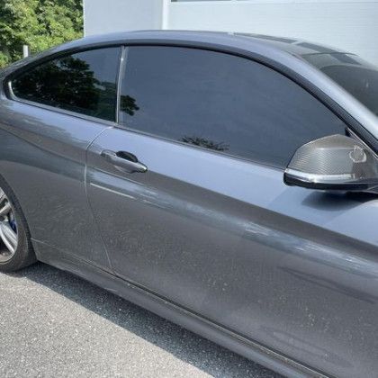 A gray bmw m4 coupe with tinted windows is parked on the side of the road.