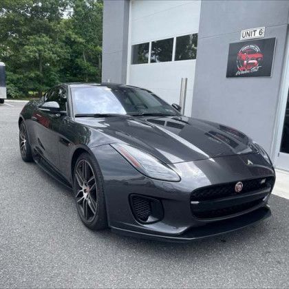 A jaguar f type is parked in front of a building.