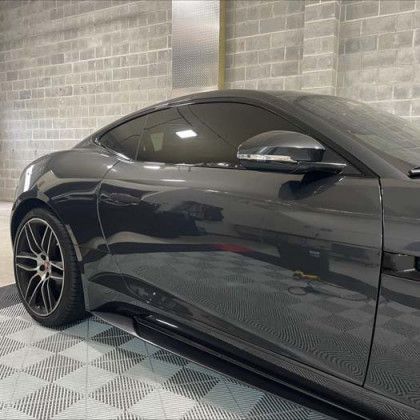 A black car is parked in a garage next to a brick wall.
