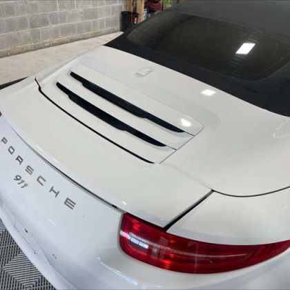 A white porsche 911 is parked in a garage