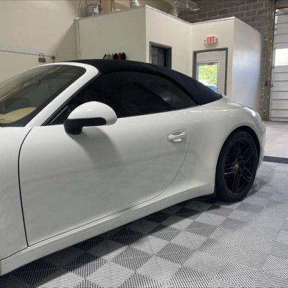 A white porsche 911 convertible is parked in a garage.