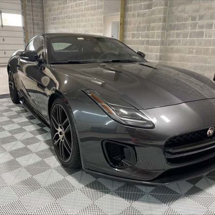 A gray jaguar f type is parked in a garage.