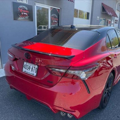 A red car is parked in front of a building.