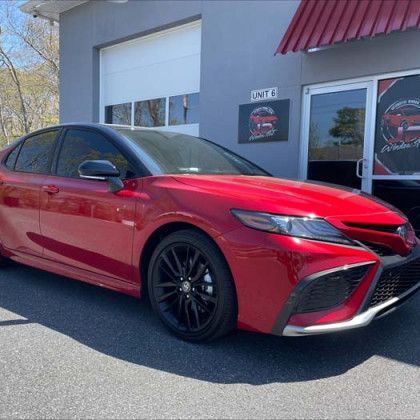 A red car is parked in front of a garage.