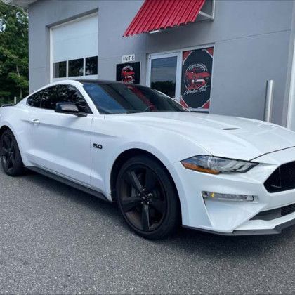 A white ford mustang is parked in front of a building.