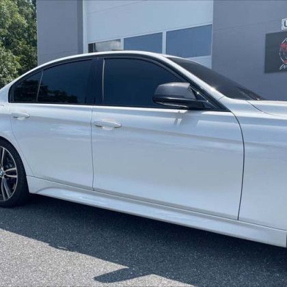 A white bmw 3 series is parked in front of a garage.