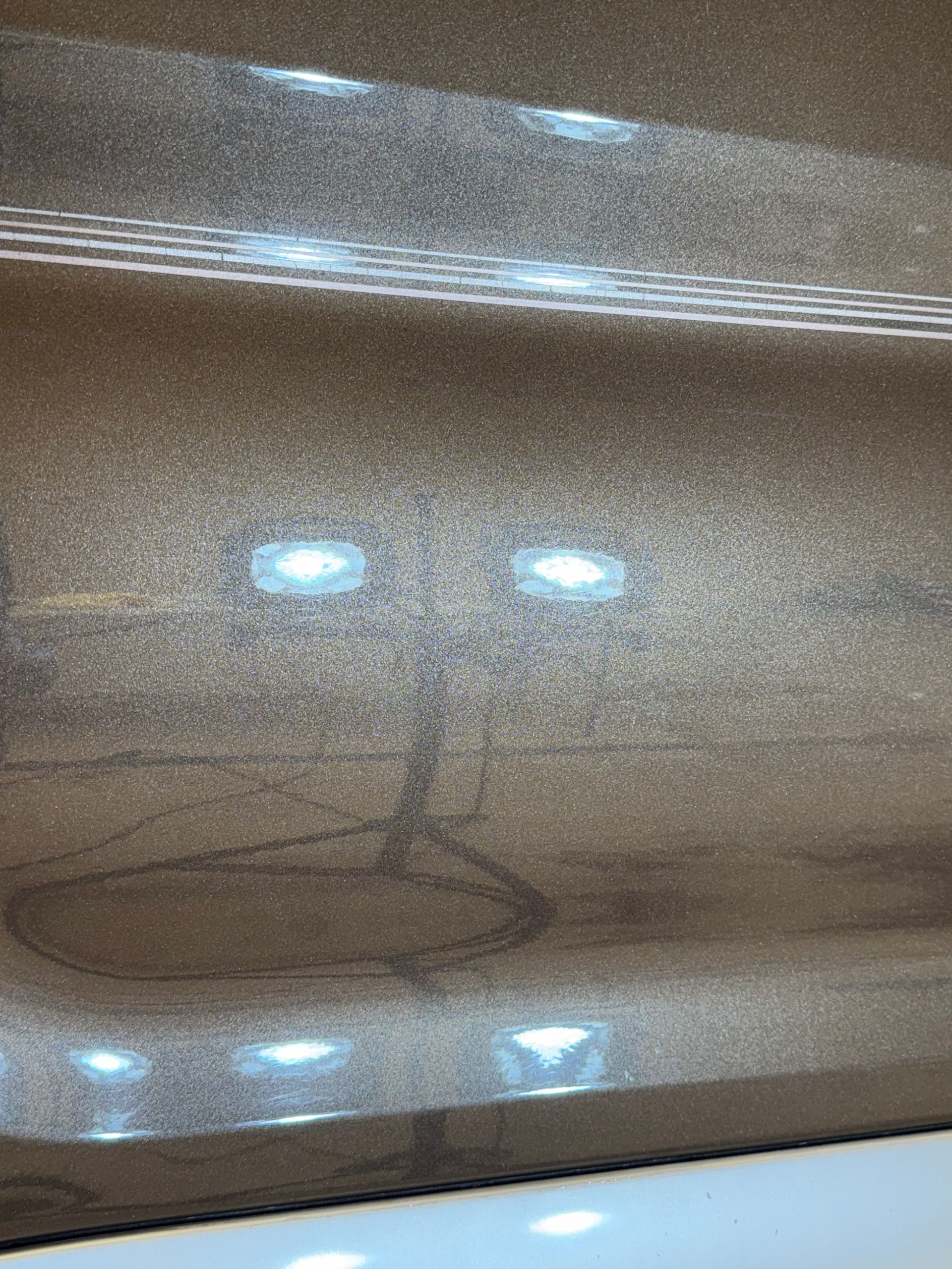 Close-up view of a metallic, bronze-colored car panel showing spider-web style cracking in the paint finish.