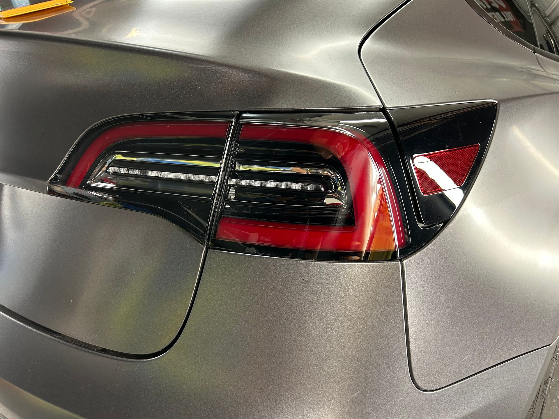 Person in protective suit and respirator spray painting a red surface.