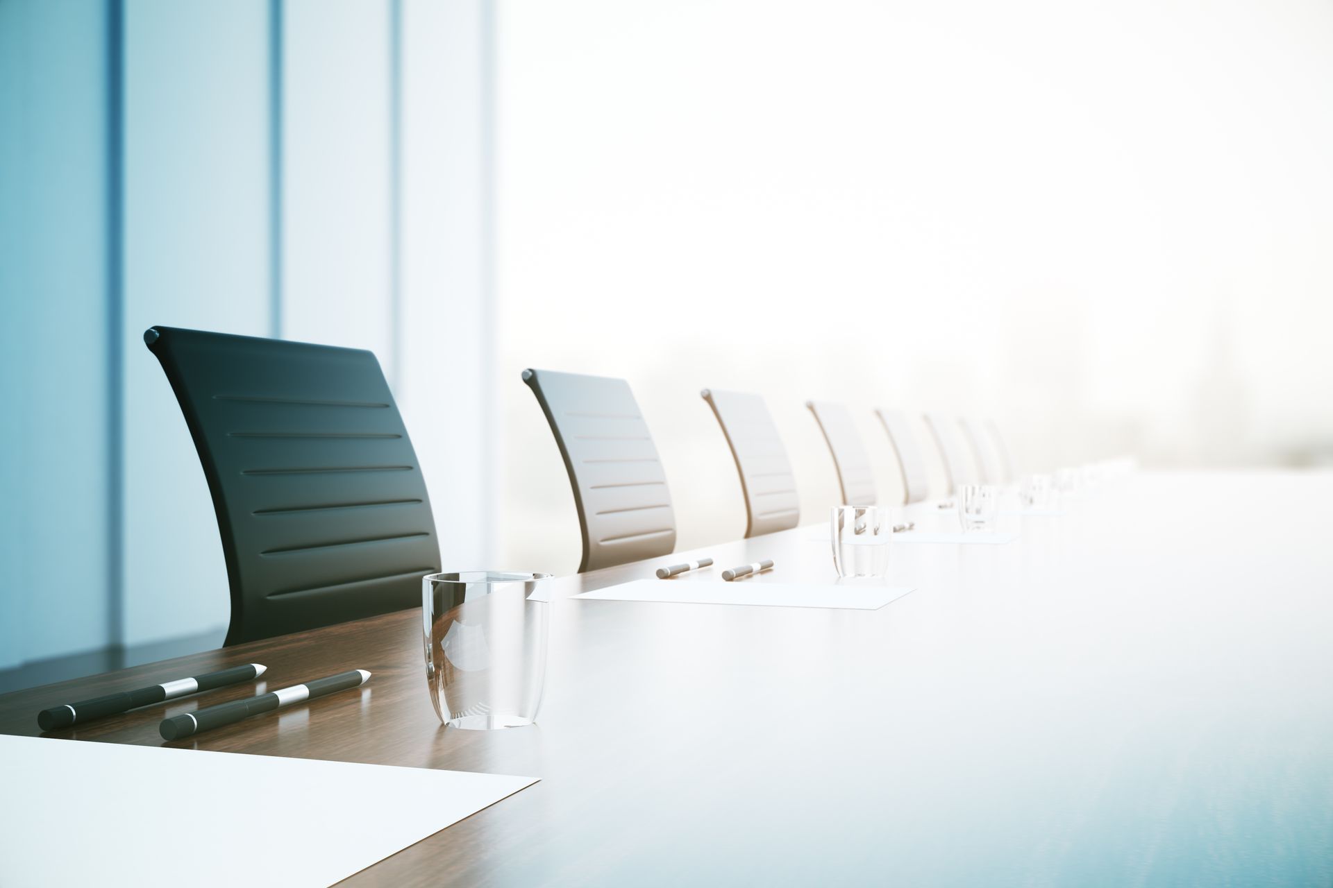 A long conference table with chairs and papers on it in a conference room.