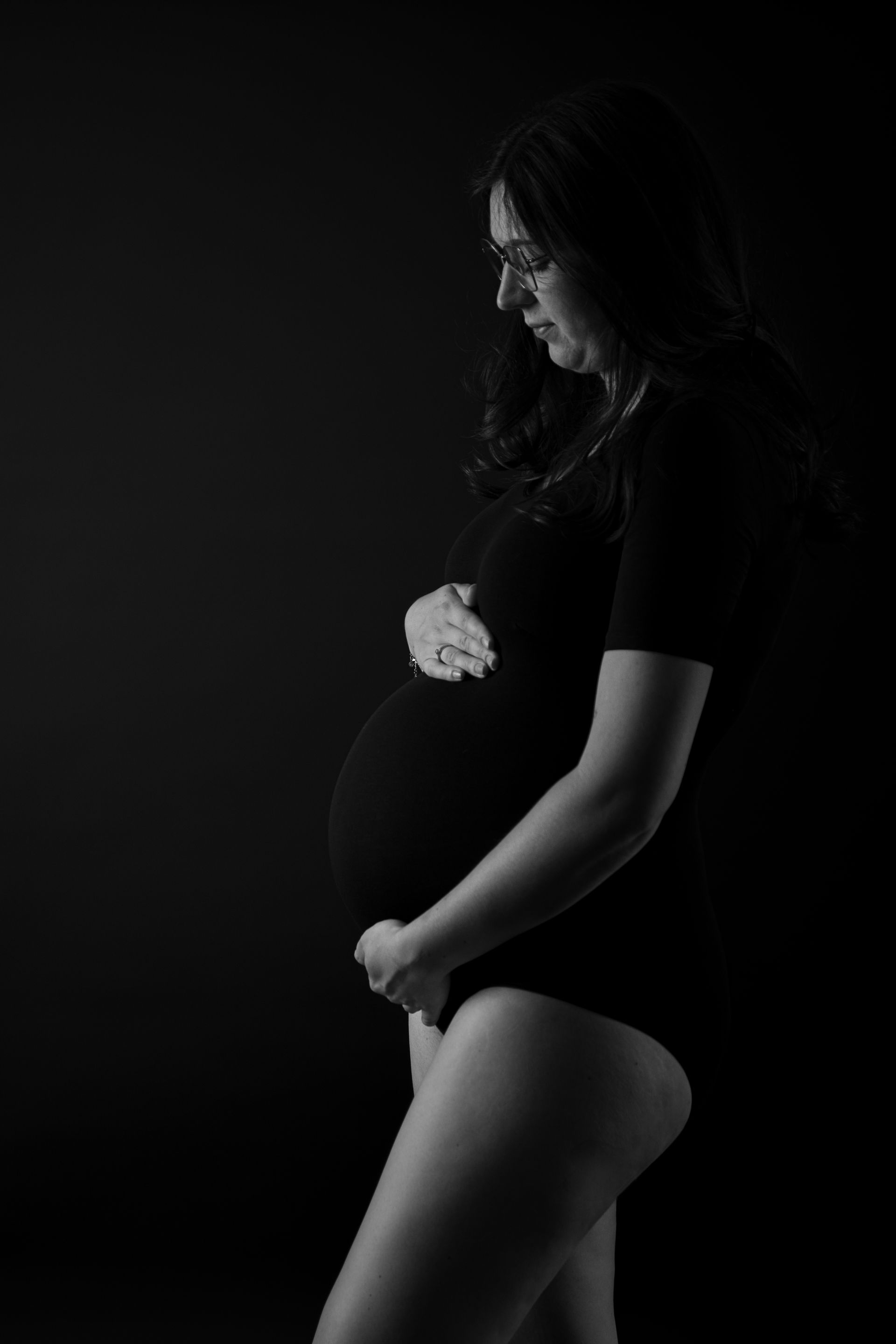 Een zwart-witfoto van een zwangere vrouw die haar buik vasthoudt.