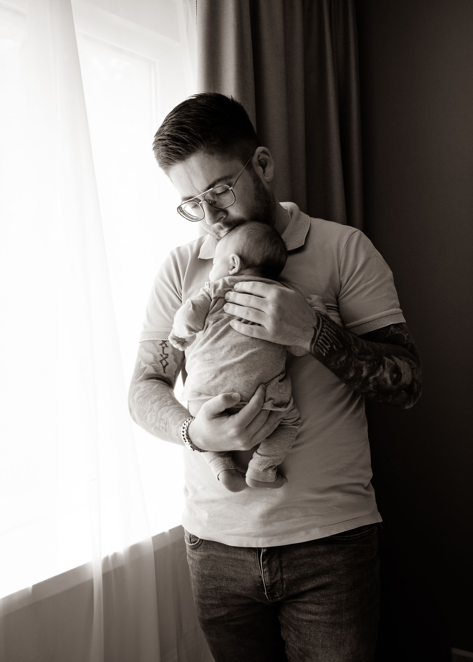 Een man houdt een baby in zijn armen voor een raam.